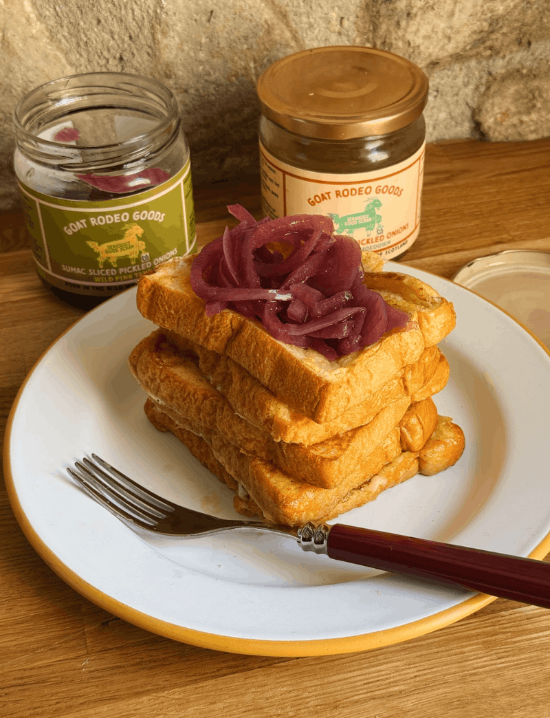 Cheesy brioche French toast sandwich topped with sharp pickled onions.