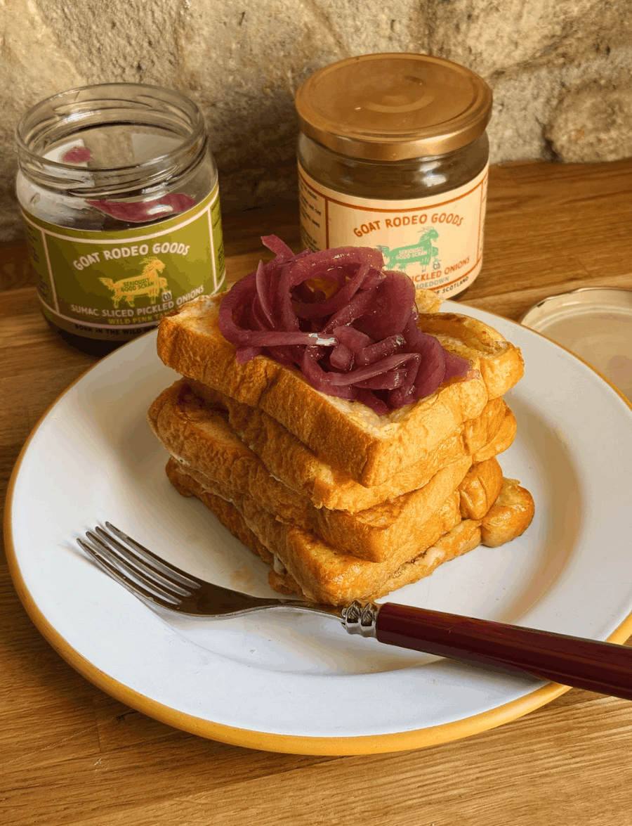 Cheesy brioche French toast sandwich topped with sharp pickled onions.